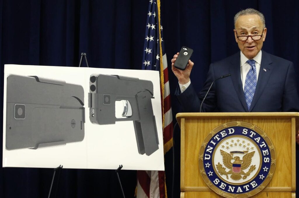 Senator Charles Schumer, upoređujući Ideal Conceal sa svojim iPhone 5S, izražava svoje protivljenje puštanju u promet oružja koje izgleda kao mobilni telefon. (Kathy Willens / Associated Press)