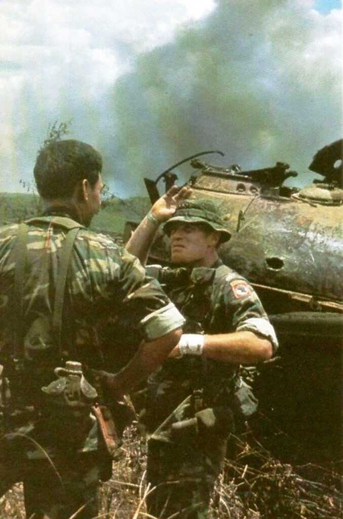 Američki savetnik i južnovijetnamski oficir iz sastava Prve padobranske brigade u razgovoru pored uništenog tenka T-54 severnovijetnamske vojske. Operacija Lamson 719