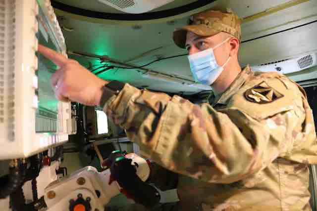 vojnik koji koristi top od 50 mm koji kontrolise ekran osetljiv na dodir uz pomoc vestacke inteligencije. copy