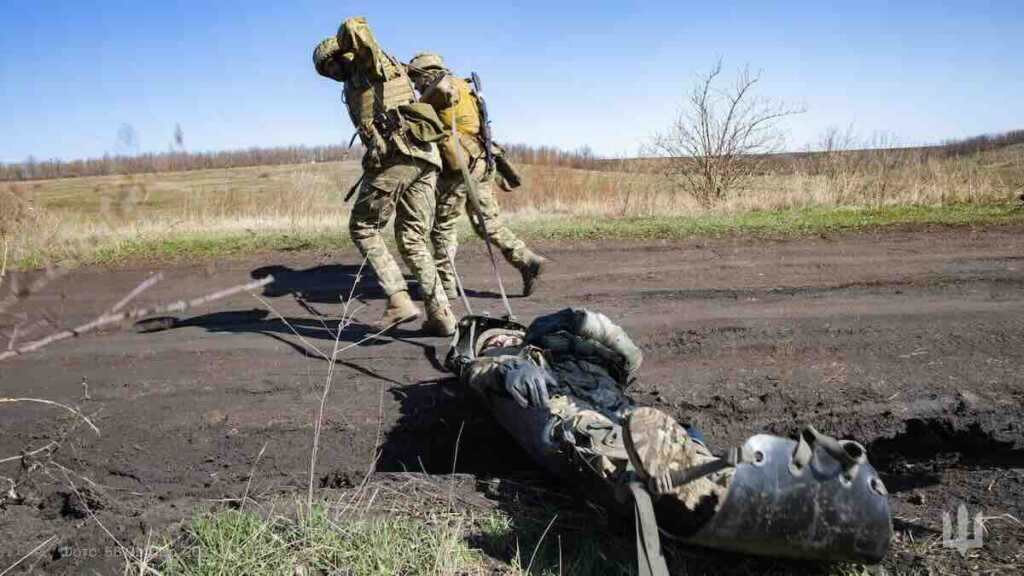 ukrajinski vojnici nose ranjenika